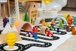 A toy town built in a children's room. Road, cars, trees and wooden blocks for children's  games in playroom. Educational game for baby and toddler in modern nursery. 