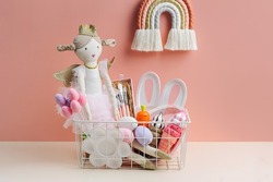Baby Easter Basket gifts. Basket with ragdoll, Easter eggs, sweets and material for creativity and art activity. Holidays decorations and gifts.
