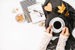 Women's hands hold a cup of coffee  wrapped in scarf  on a warm plaid. Autumn or Winter concept.  flat lay, top view