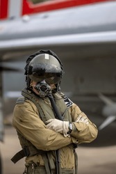 Military Fighter Pilot with helmet, visor and oxygen mask in flying suit with fighter jet. 