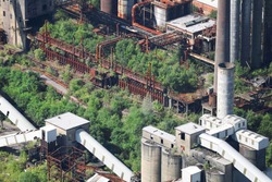 An aerial view, taken from a helicopter, of a derelict and abandoned industrial colliery site in The Valleys of South Wales. Tress and wildlife have taken over the old and now disused site.