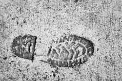 The old single imprint,footprint of shoe or boot on concrete with copy space,on black and white color