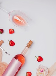 Creative summer flat lay with rose wine, delicious strawberries and beautiful peonies on the white background