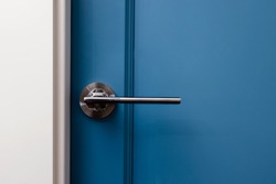 Blue colored door with handle in modern design apartment close-up