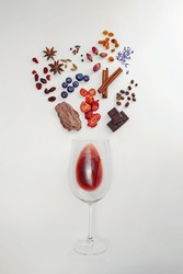 Creative composition with wine glass and possible flavor components of red wine. Flat lay composition, wine tasting concept.