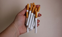 Cigarettes in hand on a white background. Yellow filter. Harm to health. It is a bad habit. The vision of a world without tobacco, tobacco and lung health. Lung cancer. Copy space for text