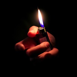 Woman Hand Holding Lit Lighter in the dark