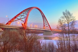 Morning at the Bugrinsky Bridge. Arched bridge with street lights at dawn on the winter banks of the Ob River. Novosibirsk, Siberia, Russia, 2022
