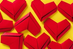 red paper hearts on yellow background,the concept of love, the day of St. Valentine's Day,Red origami hearts on yellow background,