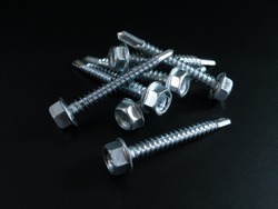 Self-tapping screws galvanized with a semicircular head and a hex head on a black background.