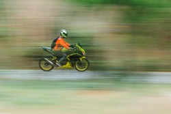 Bike rider in motion blur  panning photo of unidentified people riding motorcycle.