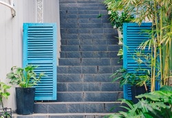 Copy space lifestyle frame photo. Building enter outdoor facade, gray stone up stairs, open wooden door painted Blue Crayola colour turquoise. Summer day time romance traditional. Greenery decorate