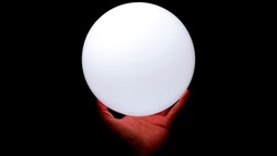Hand holding a ball of white light bulb in the dark