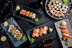 Philadelphia roll with salmon, roll canada with eel and salmon, maki rolls, sushi gunkans, sushi with salmon, tuna on dark stone table top view
