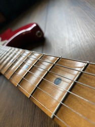 close up apple red scallop electric guitar neck and nickel stings on veneer wood background with copy space for letter in Vertical photo. business and music concept. Wallpaper or background for book.