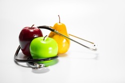 Healthy and healthy snack: green apple, ripe pear and red apple and a stethoscope or phonendoscope, diet and sports on a white background with a place for text. The concept of a healthy lifestyle, the