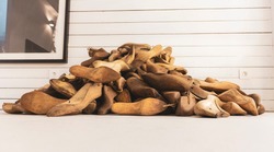 Pile of old, retro, wooden shoe molds lying on the white floor, against wooden plank wall