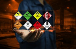 Industrial factory safety officers hold chemical hazard warning signs in their hands to remind close workers to be aware of the dangers of chemicals in dangerous goods transport and handling concept.