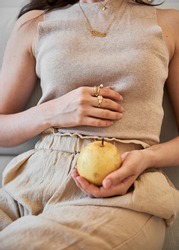 Monochromatic beige outfit for summer with a hand holding a pear.