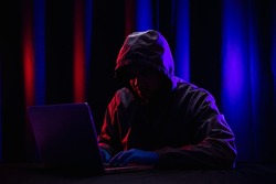 Hackers wear hoods to cover their faces. Hacking to steal important information. Use a computer to release malware viruses Ransom and harass organizations. He sitting in the dark room with neon light