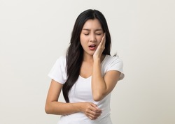 Asian woman puts her hand on her mouth and feels toothache because of tooth decay. Problems with teeth bad breath. Asian woman around 25 standing on isolated background