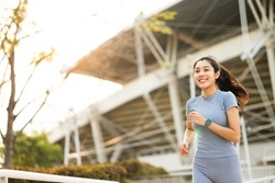 Attractive beautiful woman wearing sportswear running at sport stadium. Fit woman jogging outdoor. Workout exercise in the morning. Healthy and active lifestyle concept.