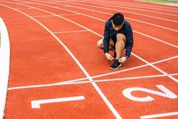 Hands man runners tie shoelaces prepared to run on track. Young asian man wearing sportswear running sport stadium.Training athlete work out at outdoor concept.