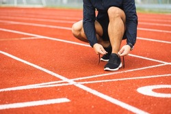 Hands man runners tie shoelaces prepared to run on track. Young asian man wearing sportswear running sport stadium.Training athlete work out at outdoor concept.