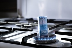 Concept of gas crisis. 2000 russian ruble bank note is burning on a kitchen stove. Cash money. High prices of natural resources. Blue flame. Utility debt. Energy war. Saving home budget. Close-up