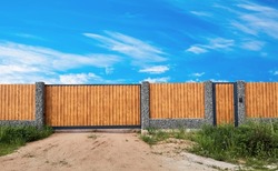 Gabion fence. Gate. Posts full of stones with sections from wooden planks. Countryside style. Exterior garden element design. Security wall. Natural materials. Isolated. Nature texture. Close-up.