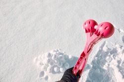 A children toy is a tool for modeling snowballs from snow. Red color plastic device. Winter outdoor kids games. Active leisure gift. Snowy background. Copy space. Banner. Ice forceps. New year time.