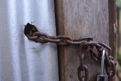 rusty chains hold the door closed. old rotted chain and padlock on the carriage. Rust lock and chain on fence for house protection. Old and rusty chain texture