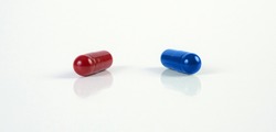 Red and Blue Capsule like those in the matrix. Macro of medicine capsules on white background.