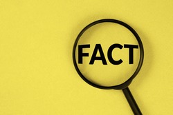 Fact - word through magnifying glass on yellow background.