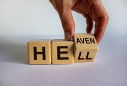 Hell or heaven. Hand turns a cube and changes the word 'hell' to 'heaven'. Concept. Beautiful white background, copy space.