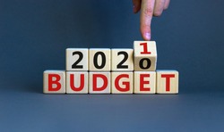Business concept of planning 2021. Male hand flips wooden cube and change the inscription 'BUDGET 2020' to 'BUDGET 2021'. Beautiful grey background, copy space.