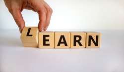 Learn or earn. Hand flips a cube and changes the word 'earn' to 'learn' or vice versa. Beautiful white background. Business concept. Copy space.