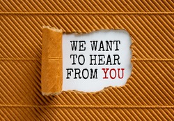 The text 'we want to hear from you' appearing behind torn brown paper. Beautiful background. Business concept.