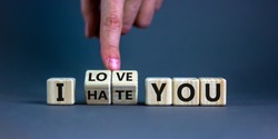 Hand turns cubes and changes the expression 'I hate you' to 'I love you'. Beautiful grey background, copy space. Concept.