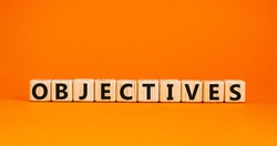 'Objectives' written on wooden blocks. Business concept. Copy space. Beautiful orange background.