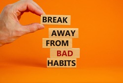 Time to break bad habits. Wooden blocks with words 'break away from bad habits'. Male hand. Beautiful orange background, copy space. Business and psychological concept.