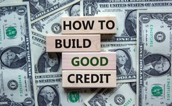 Symbol of building success foundation. Stack of wooden blocks. Words 'how to build good credit'. Beautiful background from dollar bills. Business and build good credit concept.