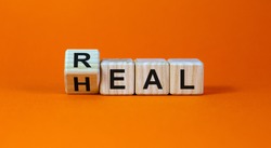 Real heal symbol. Fliped a wooden cube with words 'Real heal'. Beautiful orange background, copy space. Medical and real heal concept.