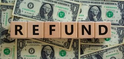 Refund symbol. Concept word 'refund' on wooden cubes on a beautiful background from dollar bills. Business and refund concept.