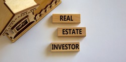 Real estate investor symbol. Wooden blocks with words 'Real estate investor' near miniature house. Beautiful white background. Business and real estate investor concept, copy space.