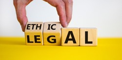 Ethical or legal symbol. Businessman hand turns wooden cubes and changes the word 'legal' to 'ethical' on a beautiful yellow table, white background. Business and ethical or legal concept. Copy space.