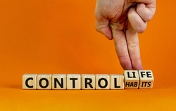 Control habits symbol. Businessman hand turns wooden cubes and changes words 'control habits' to 'control life'. Beautiful orange background, copy space. Business and control habits concept.