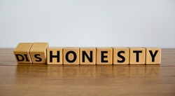 Honesty or dishonesty symbol. Turned cube and changed the word 'dishonesty' to 'honesty'. Beautiful wooden table, white background. Business and honesty or dishonesty concept. Copy space.