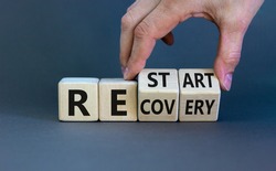 Recovery and restart symbol. Businessman hand turns cubes and changes the word 'recovery' to 'restart'. Beautiful grey background. Business and recovery - restart concept. Copy space.