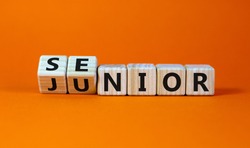 From junior to senior symbol. Turned cubes and changed the word 'junior' to 'senior'. Beautiful orange background, copy space. Business and junior or senior concept.